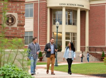 Michael Kurtz, associate professor of economics, institute for management studies, pre-health, and pre-medicine, talks with students outside of the Lynn Science Center.